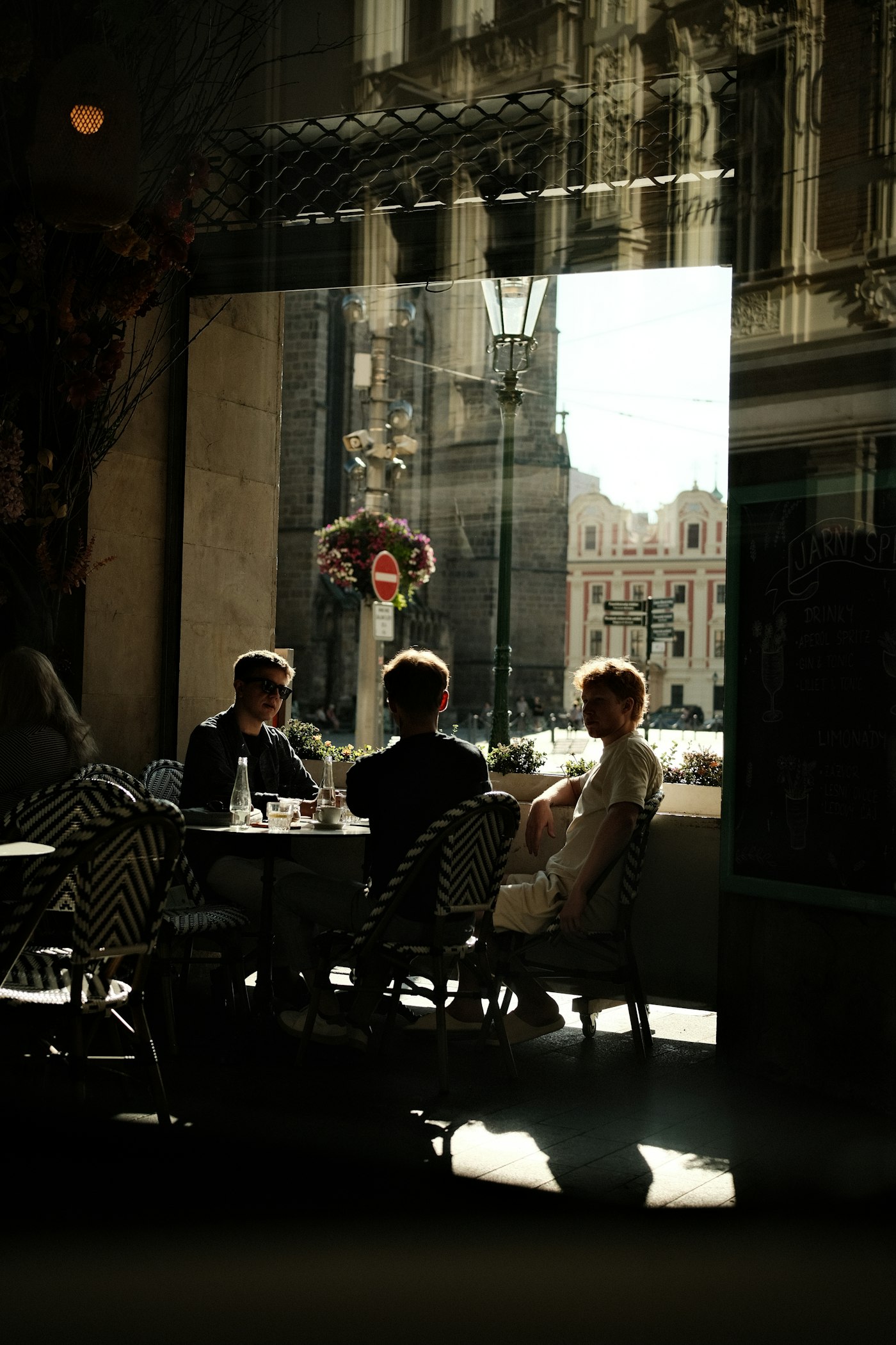Des voyageurs en terrasse de café, baignés de lumière chaude.
