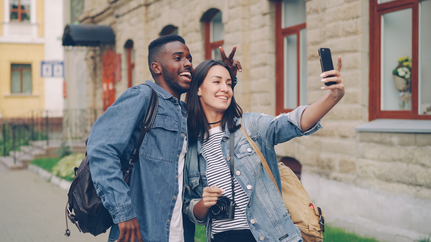 Deux voyageurs qui se prennent en photo dans une rue.